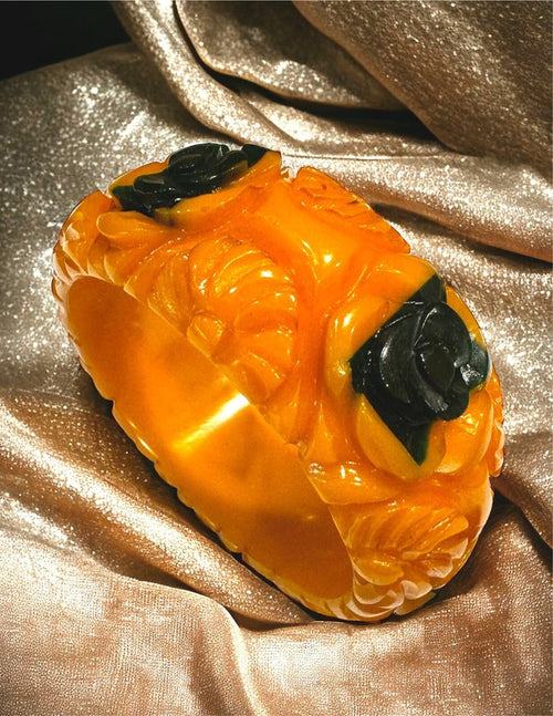 Carved golden amber Bakelite bracelet with inset green Bakelite roses
